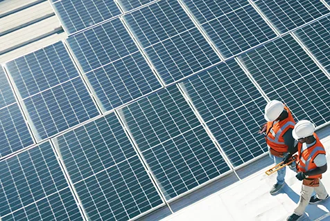 Construction workers walking past solar panels